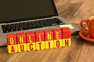 Träklossar med texten ONLINE AUCTION framför en laptop.