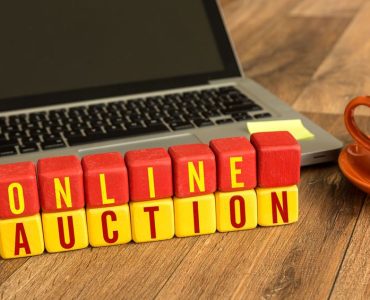 Träklossar med texten ONLINE AUCTION framför en laptop.